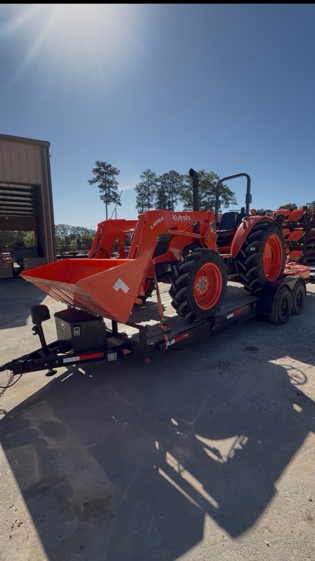 Orange Kubota tractor loaded on a flatbed at a dealership