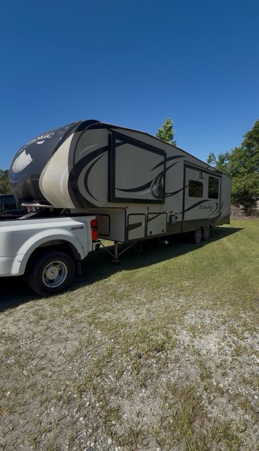 Large fifth-wheel RV camper being towed by a white 4x4 truck